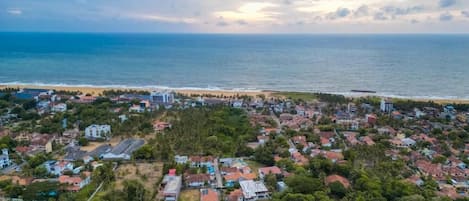An aerial view of a coastal town with residential buildings, a beach, and a clear view of the ocean.