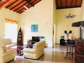 A spacious living room with a high ceiling, a television, a sofa, a coffee table, and a chandelier. - Ayana Beach Garden (Negombo)