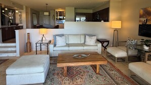 Ein modernes Wohnzimmer mit Sofa, Hocker, Couchtisch und Teppich.
