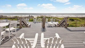 A wooden deck with white chairs and tables, overlooking a beach. - Oceanfront Luxury 2BR Litchfield Beach Escape (Pawleys Island)