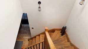 Una scala in legno con corrimano, una piccola finestra in cima e un lampadario sopra.