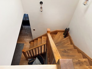 A wooden staircase with a handrail, a small window at the top, and a light fixture above.