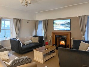 A living room with a fireplace, two sofas, a coffee table, and a television mounted above the fireplace. - 4 bedroom accommodation in Inverkip, near Greenock (Inverkip, near Greenock)