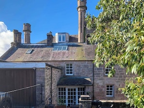 A stone building with multiple chimneys, a small window, and a door. - 4 bedroom accommodation in Inverkip, near Greenock (Inverkip, near Greenock)
