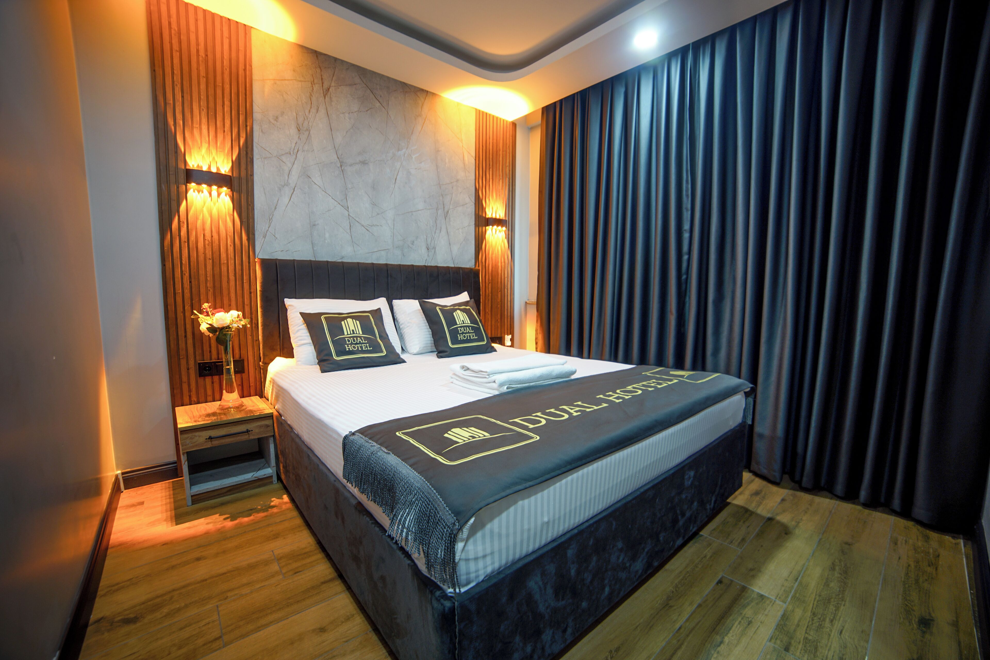 A hotel room with a large bed, wooden headboard, and a nightstand with a lamp.