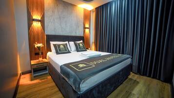 A hotel room with a large bed, wooden headboard, and a nightstand with a lamp.