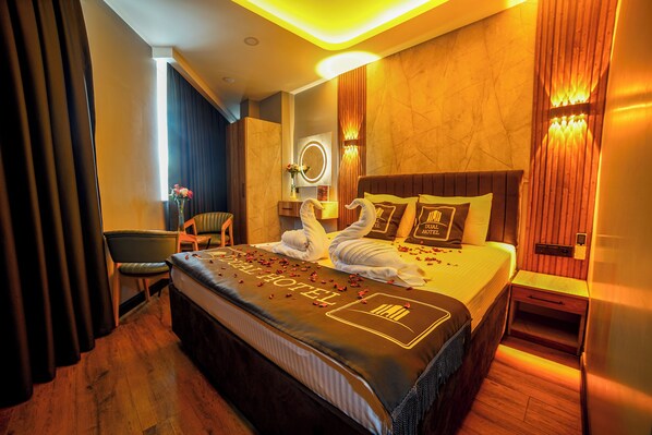 A hotel room with a large bed, a bedside table, a chair, and a mirror. - Dual Hotel (Istanbul)
