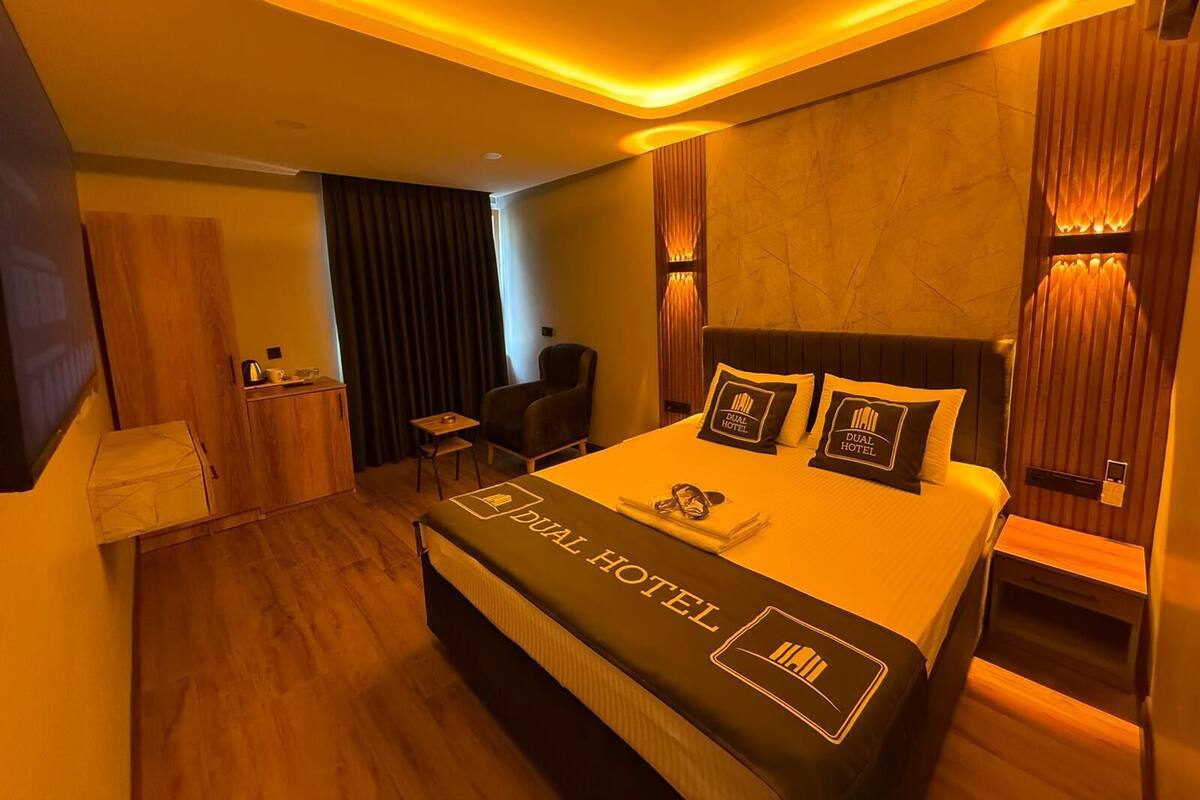 A hotel room with a bed, a chair, a desk, and a TV.
