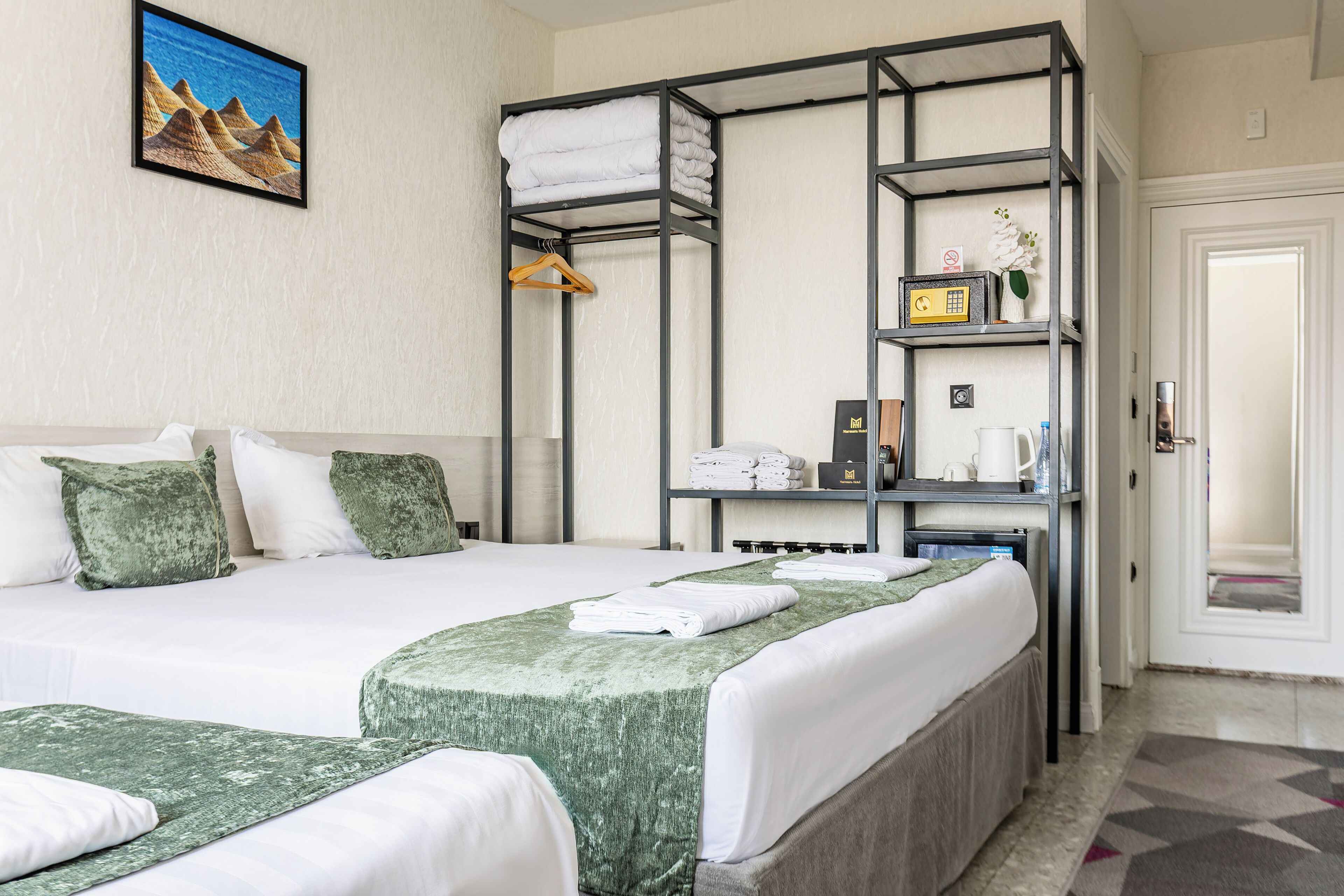 Een hotelkamer met een stapelbed, een enkel bed en een klein bureau met een koffiezetapparaat.