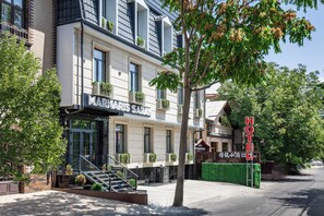 Egy modern homlokzatú szálloda, amelynek a bejáratához vezető lépcsője jól látható, és egy tábla jelzi a szálloda nevét.