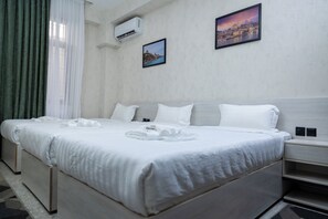 Habitación de hotel con una cama grande, una mesita de noche y aire acondicionado de pared.