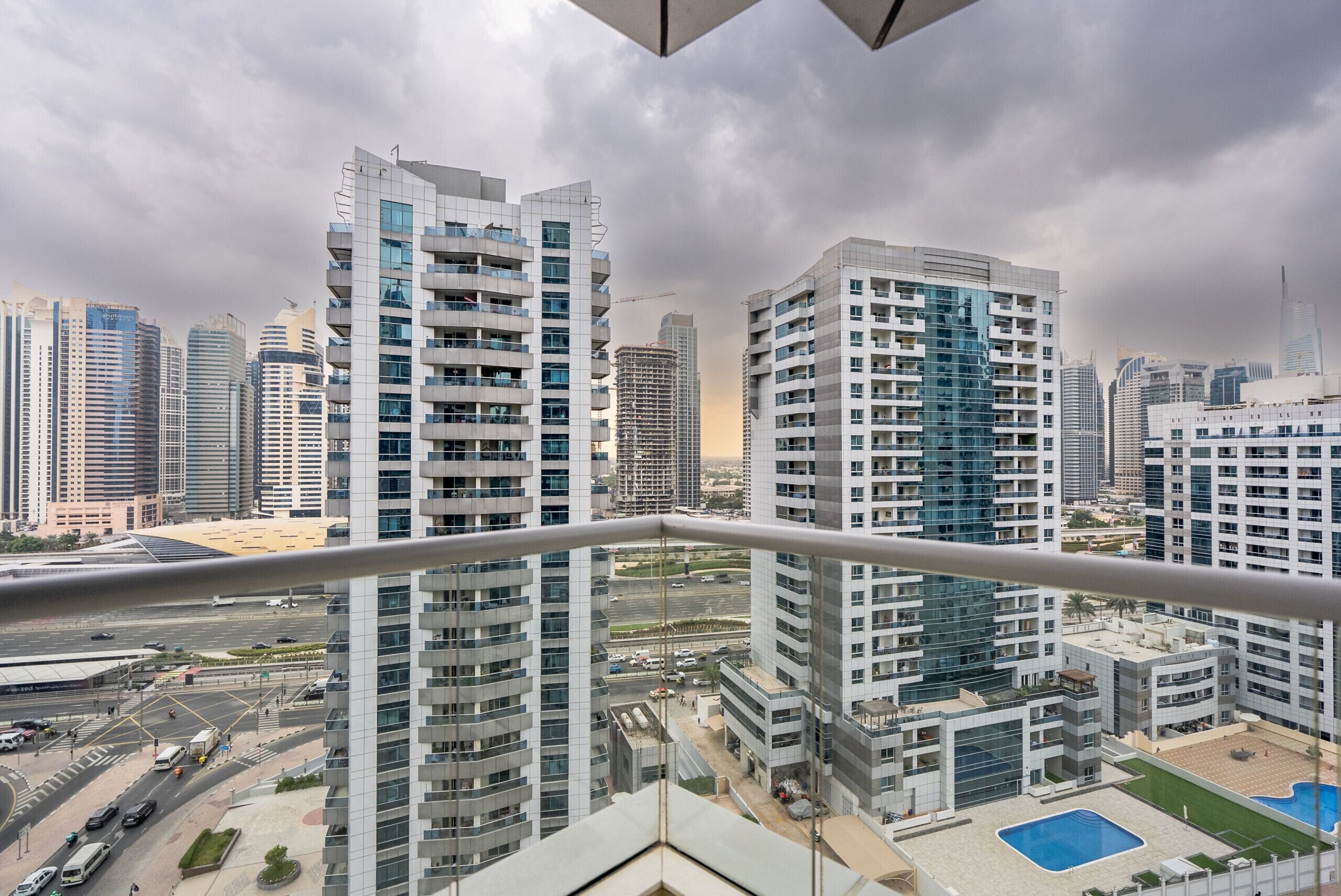 Un immeuble de grande hauteur doté de nombreux balcons et d’un espace piscine.