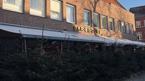 Ein Backsteinhaus mit einem Schild, auf dem „BARBEQUE“ steht, und einer überdachten Außenbereich-Sitzgelegenheit mit Weihnachtsbäumen.