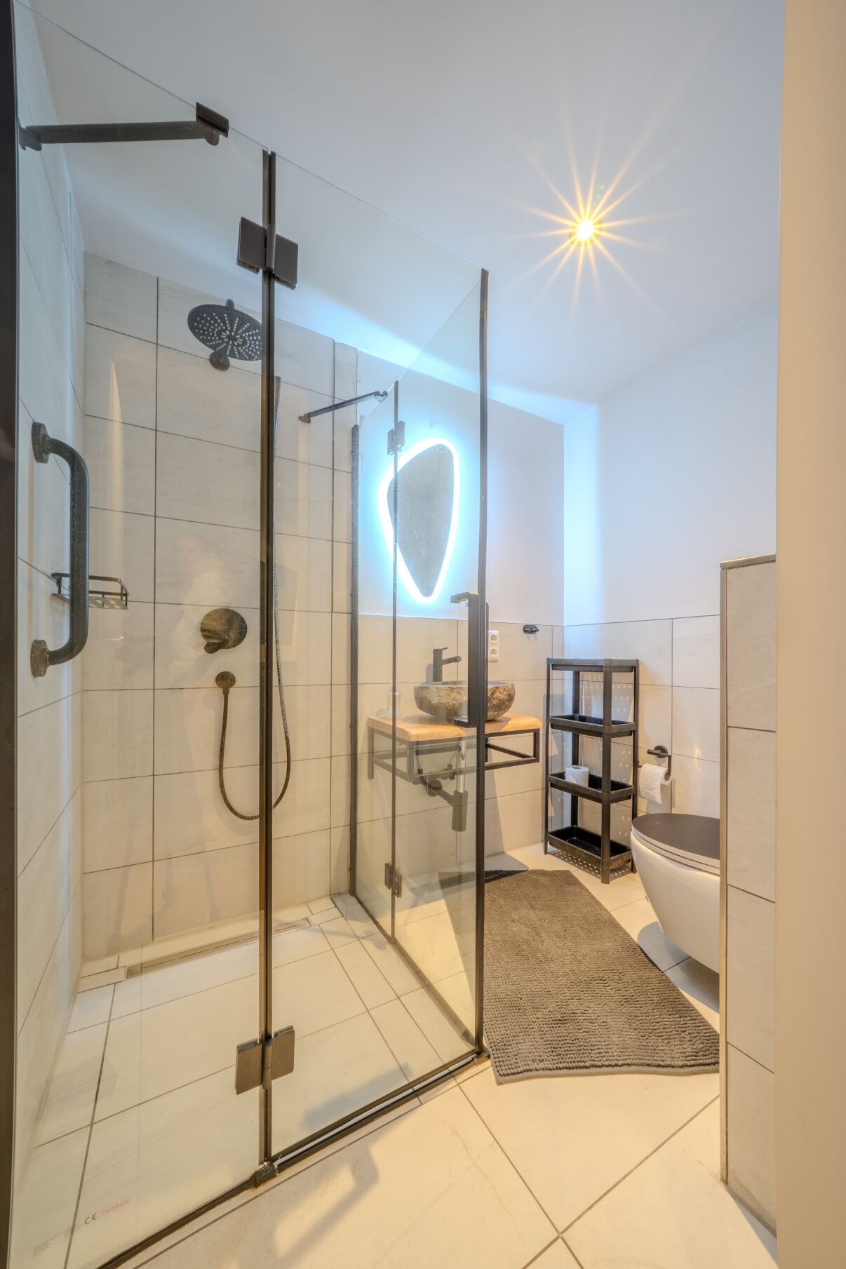 Een moderne badkamer met een douchecabine van glas, een houten wastafelmeubel en een toilet.