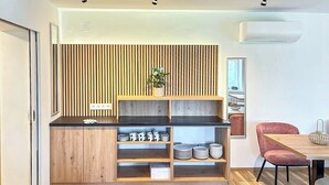Een moderne keuken met houten kastjes, een zwart aanrecht en een inbouwplank met borden en bekers.