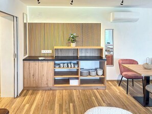 Eine moderne Küche mit Holzschränken, einer schwarzen Arbeitsplatte und einer eingebauten Regaleinheit mit Tellern und Tassen.