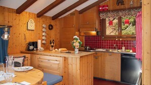 Een gezellige keuken met houten kastjes, een eettafel met blauwe kussens en een rode betegelde spatwand.