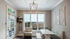 Uma cozinha moderna com uma janela grande, um candelabro e um banco.
