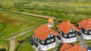 A coastal property with multiple houses featuring red-tiled roofs and white walls, surrounded by lush greenery and a view of the sea. - "Alitta" - 240m from the sea by Interhome (Bogense)