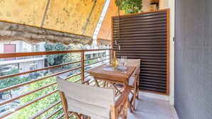 Un balcon avec une table en bois, des chaises et une bouteille de vin.