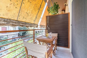 A balcony with a wooden table, chairs, and a bottle of wine. - Hephaestus - Luxury & Modern Apartment in Psychiko/Athens (Athina)