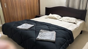 A neatly made bed with a black and white duvet, two pillows, and two folded towels on the bed. - The Yellow Gate - 2BHK - New Apartment - Near Banashankari (Bengaluru)