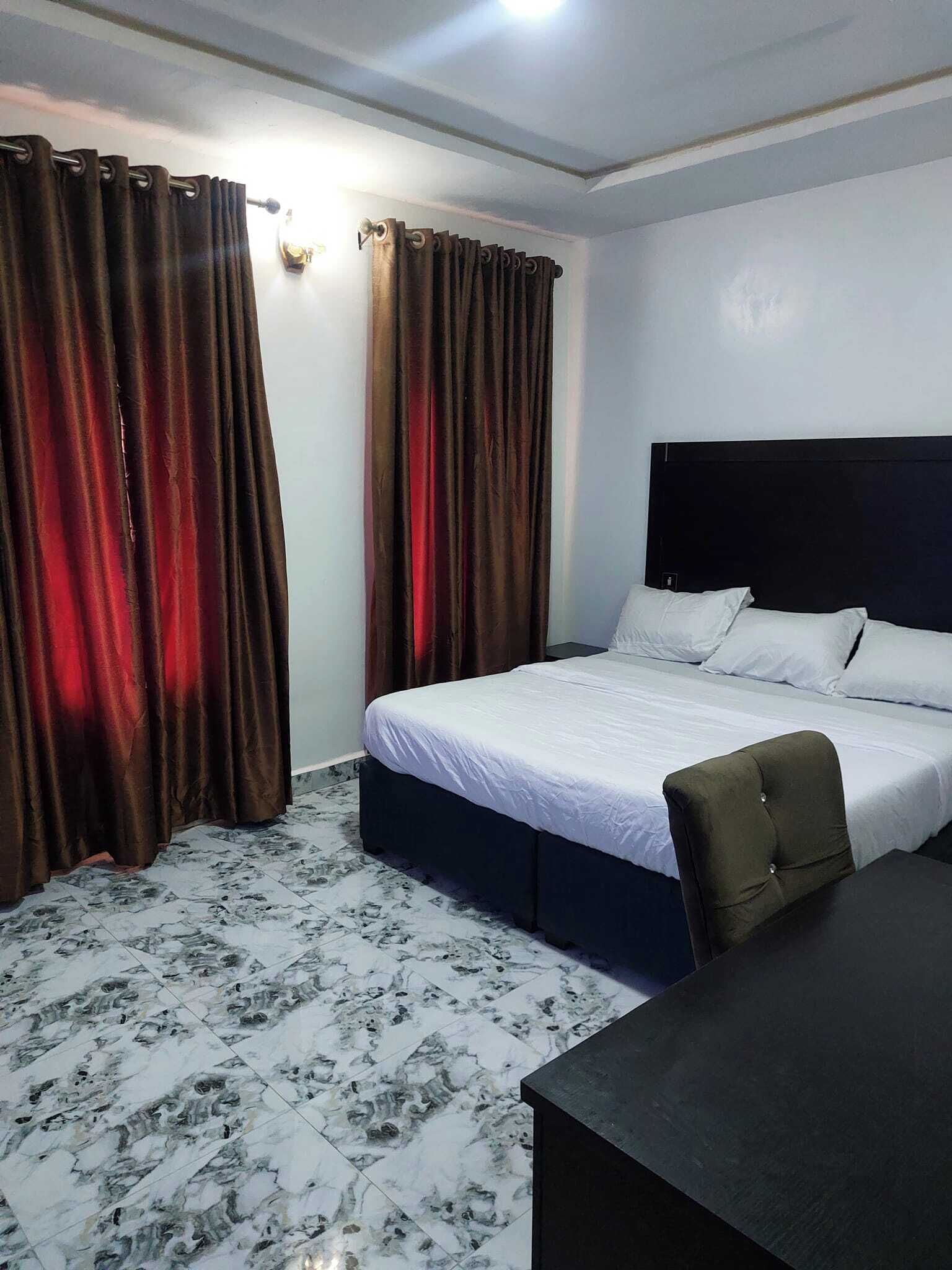 Una habitación de hotel con una cama, un escritorio y cortinas.