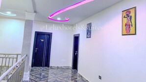 A hotel hallway with a marble floor, a staircase with a railing, and a ceiling with a circular light fixture. - LELUX HOTELS (Umuahia)