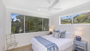 A bedroom with a large window, a bed, a chair, and a nightstand. - Sandy Feet Retreat - 1 Min To Beach (COPACABANA)