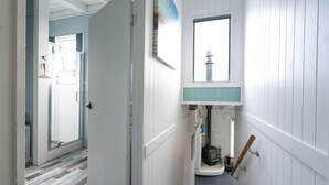 A narrow hallway with white wooden walls, a small window, and a wooden door. - Kiwizone Hideaway. Full home- self checkin. (Kerikeri)