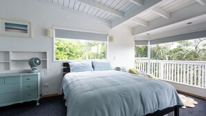 A bedroom with a bed, a dresser, a fan, and a window with a view of greenery. - Kiwizone Hideaway. Full home- self checkin. (Kerikeri)