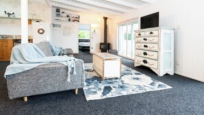 A cozy living room with a grey sofa, a white cabinet with drawers, a small wooden table, and a patterned rug. - Kiwizone Hideaway. Full home- self checkin. (Kerikeri)