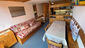 Un espacio habitable compacto con sofá, mesa de comedor y kitchenette.