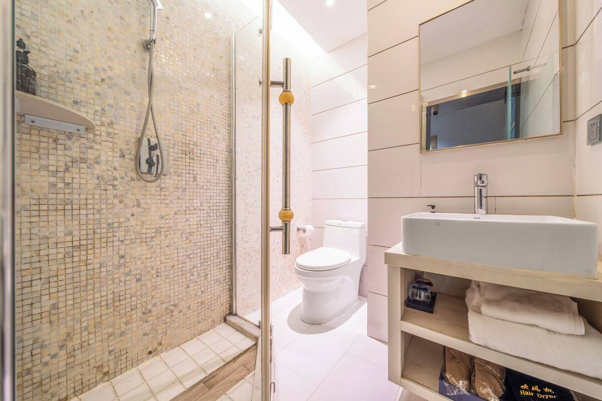 Un baño moderno con ducha, inodoro, lavamanos y espejo.