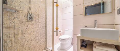 A modern bathroom with a shower, toilet, sink, and a mirror.