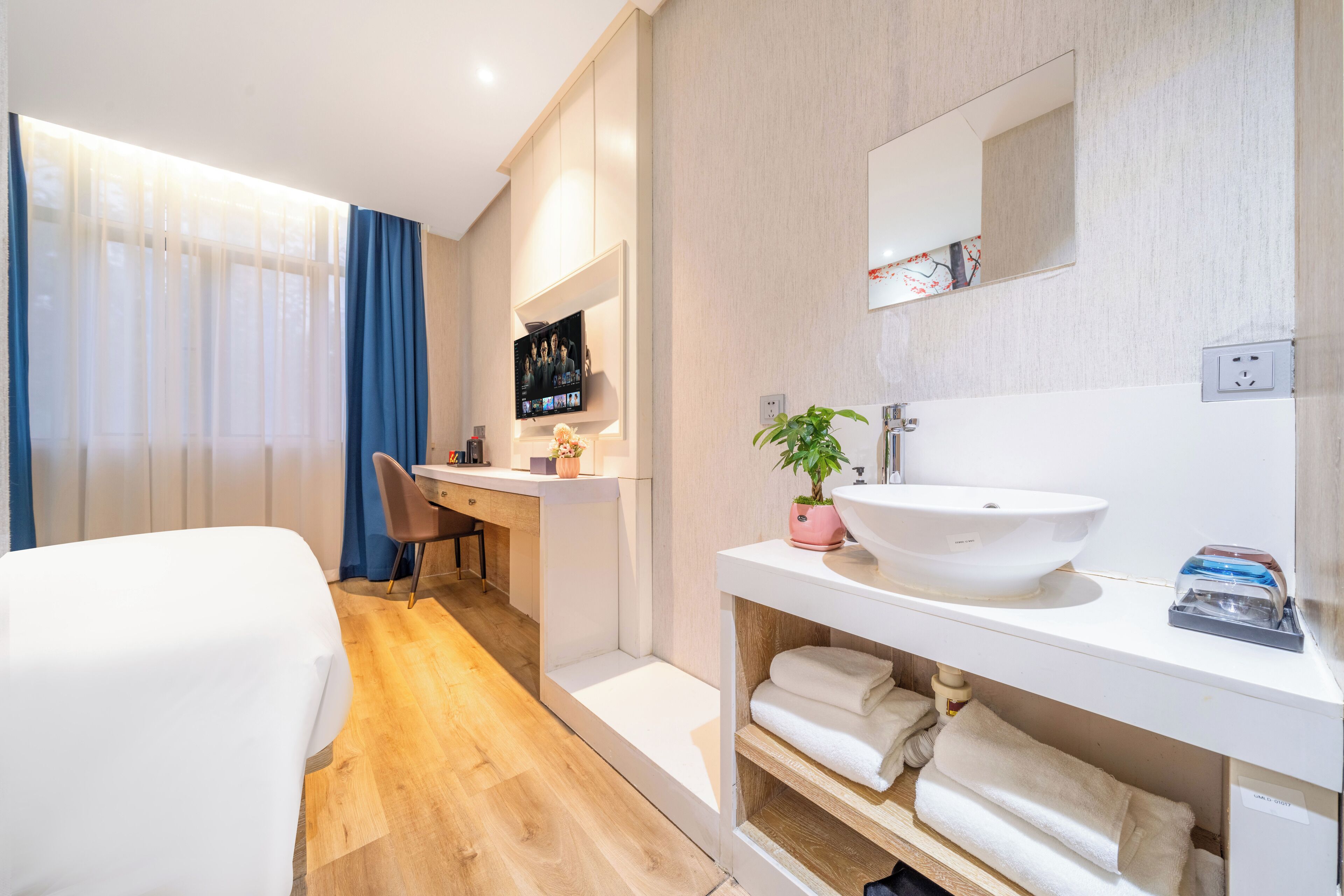 Une chambre d’hôtel moderne équipée d  ’un lit, d’un bureau, d’une télévision et d’une salle de bain avec un lavabo et un porte-serviettes.