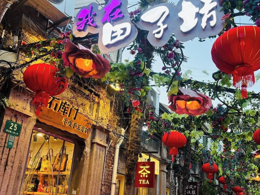 Una calle con decoraciones tradicionales, como farolillos rojos y arreglos florales.