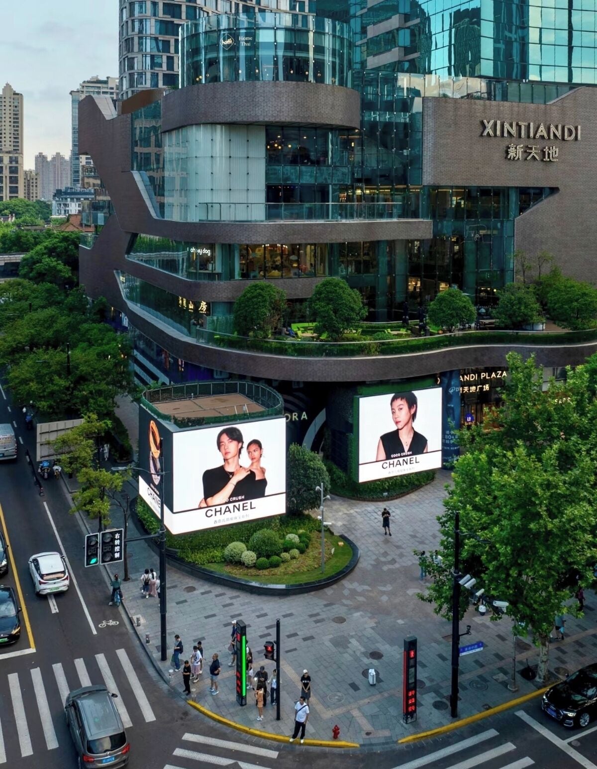 A modern building with large Chanel advertisements, a pedestrian area, and a crosswalk.