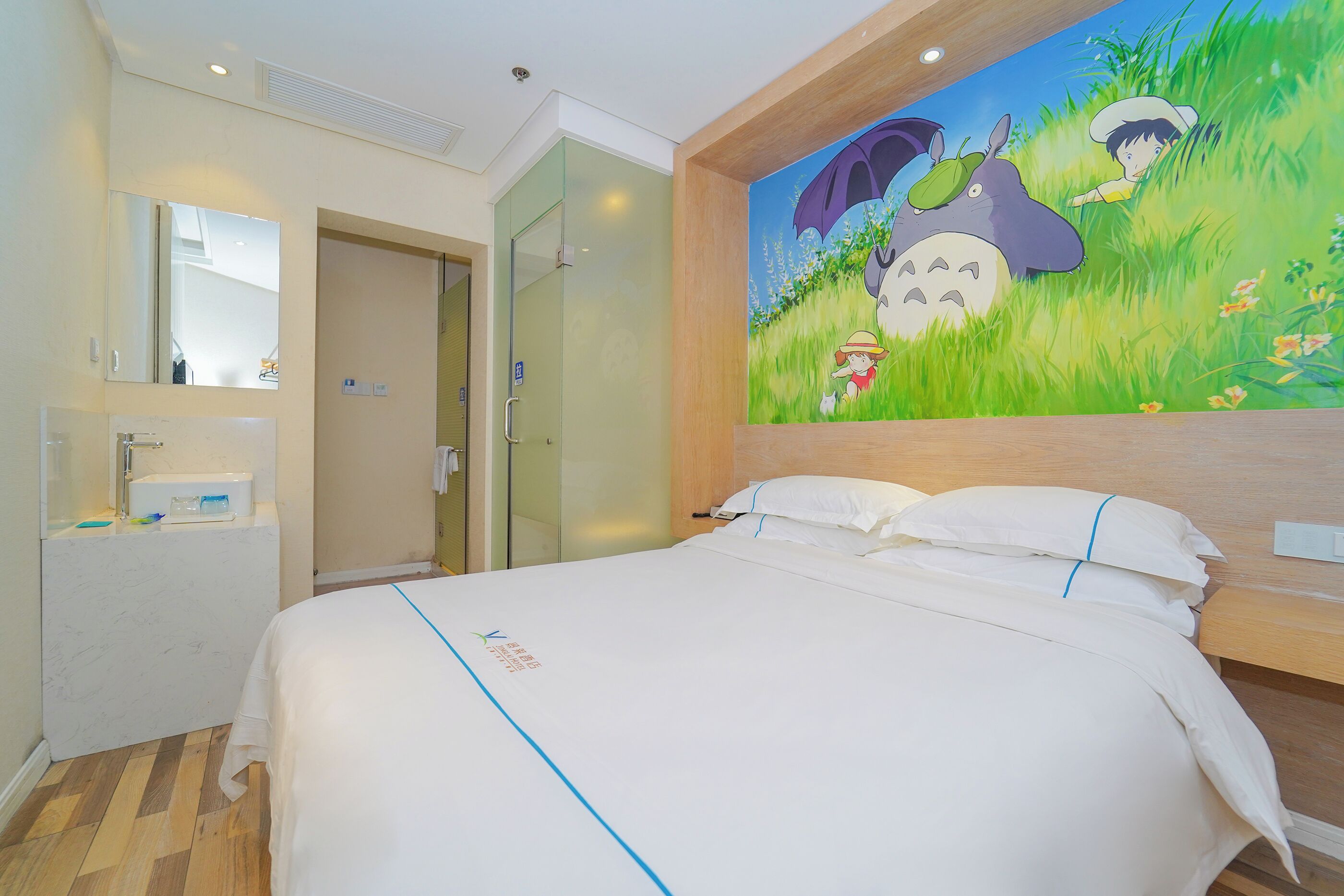 A hotel room with a bed, a bathroom with a mirror, and a wall mural.