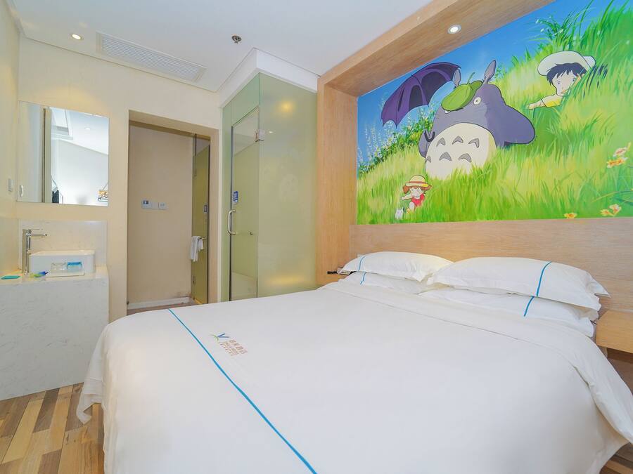 A hotel room with a bed, a bathroom with a mirror, and a wall mural.