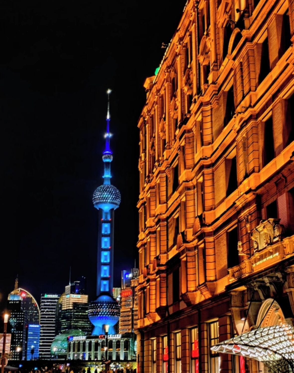 A nighttime cityscape with a prominent tower and classical architecture.