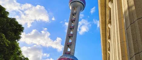 A tower with a spherical observation deck, a spire, and a lattice structure, and a building with classical architecture.
