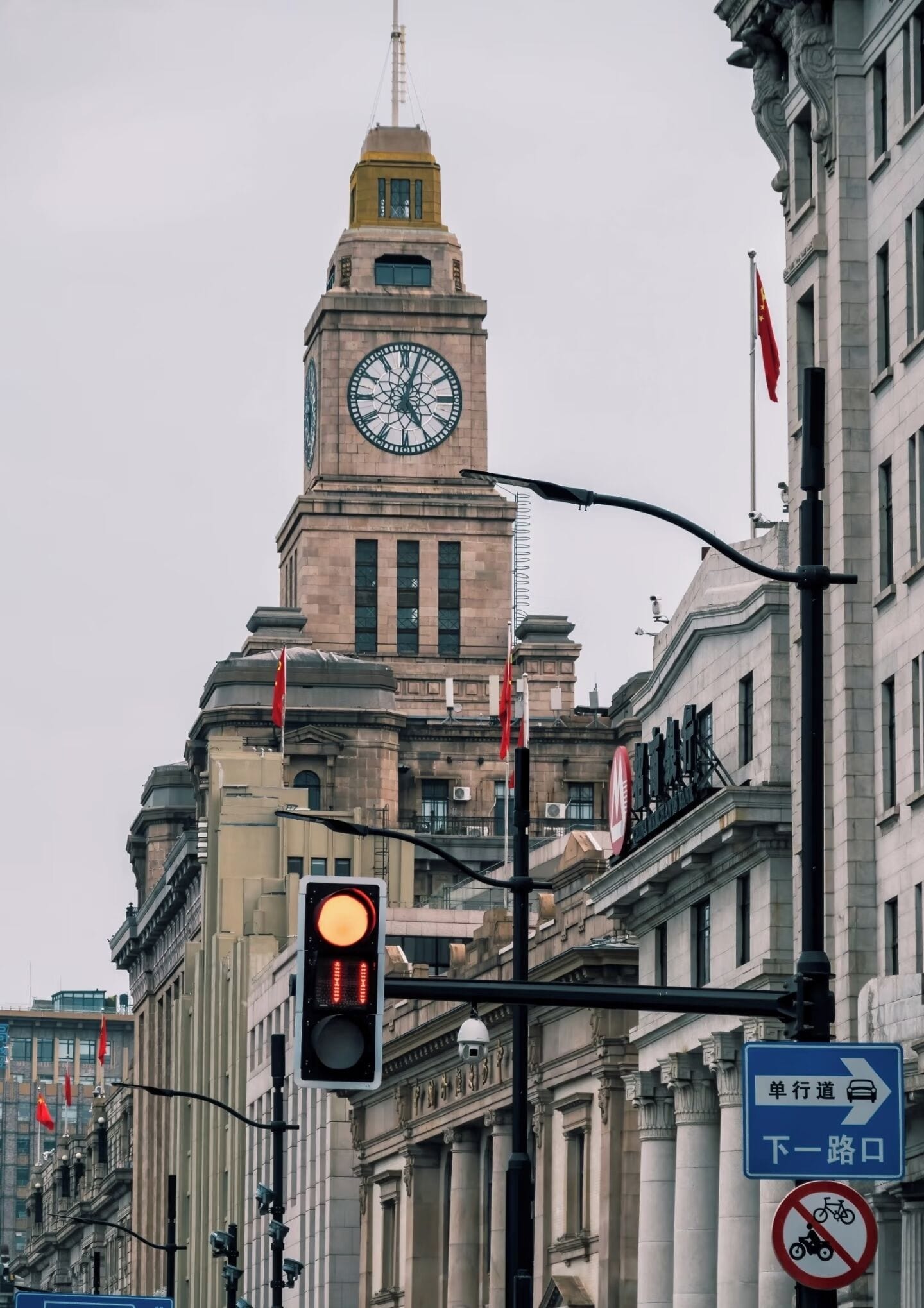 Ein historisches Gebäude mit einem markanten Glockenturm, Ampeln und Hinweisschildern.