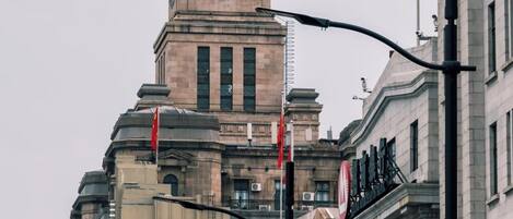 A historic building with a prominent clock tower, traffic lights, and directional signage.