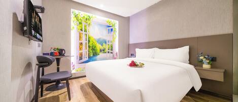 Habitación de hotel moderna con una cama grande, un escritorio con una silla, un televisor de pantalla plana y una ventana con vistas a zonas verdes.