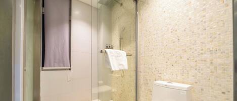 A bathroom with a glass-enclosed shower, a toilet, and a tiled wall.