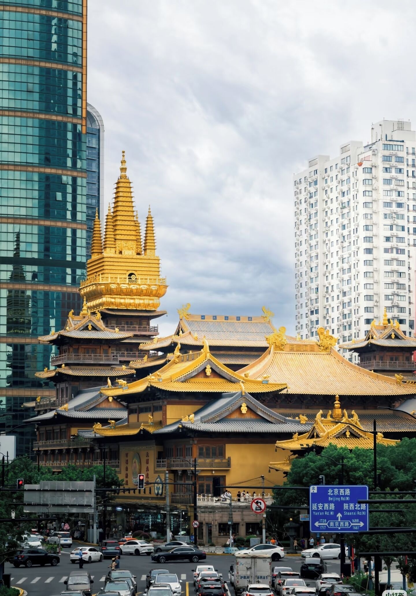 A traditional building with a golden spire, modern high-rise buildings, and a busy street with cars.