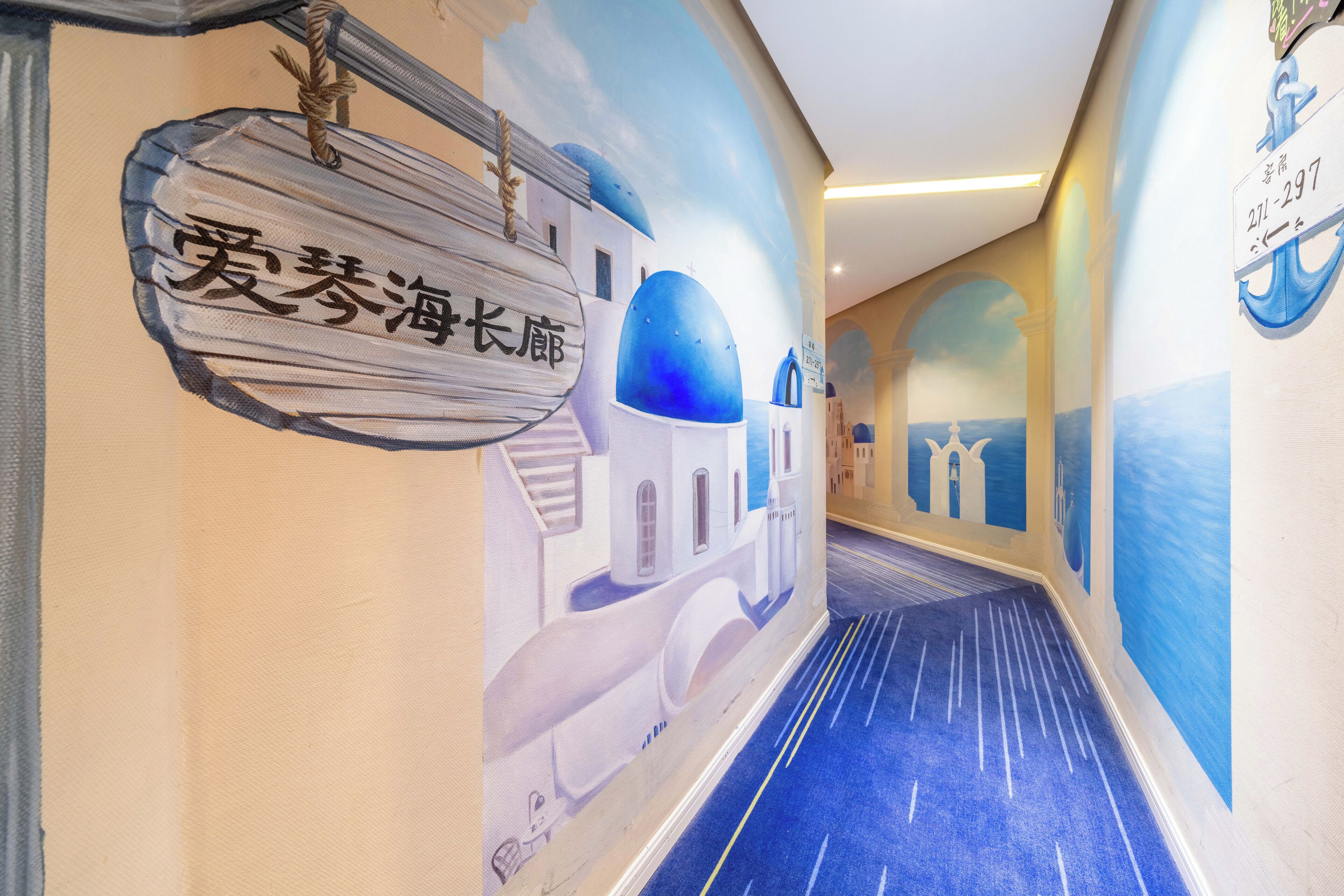 A hallway with a mural of a coastal scene, including a building with blue domes and a sign with Chinese characters.