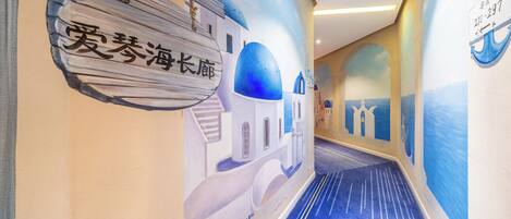 A hallway with a mural of a coastal scene, including a building with blue domes and a sign with Chinese characters.