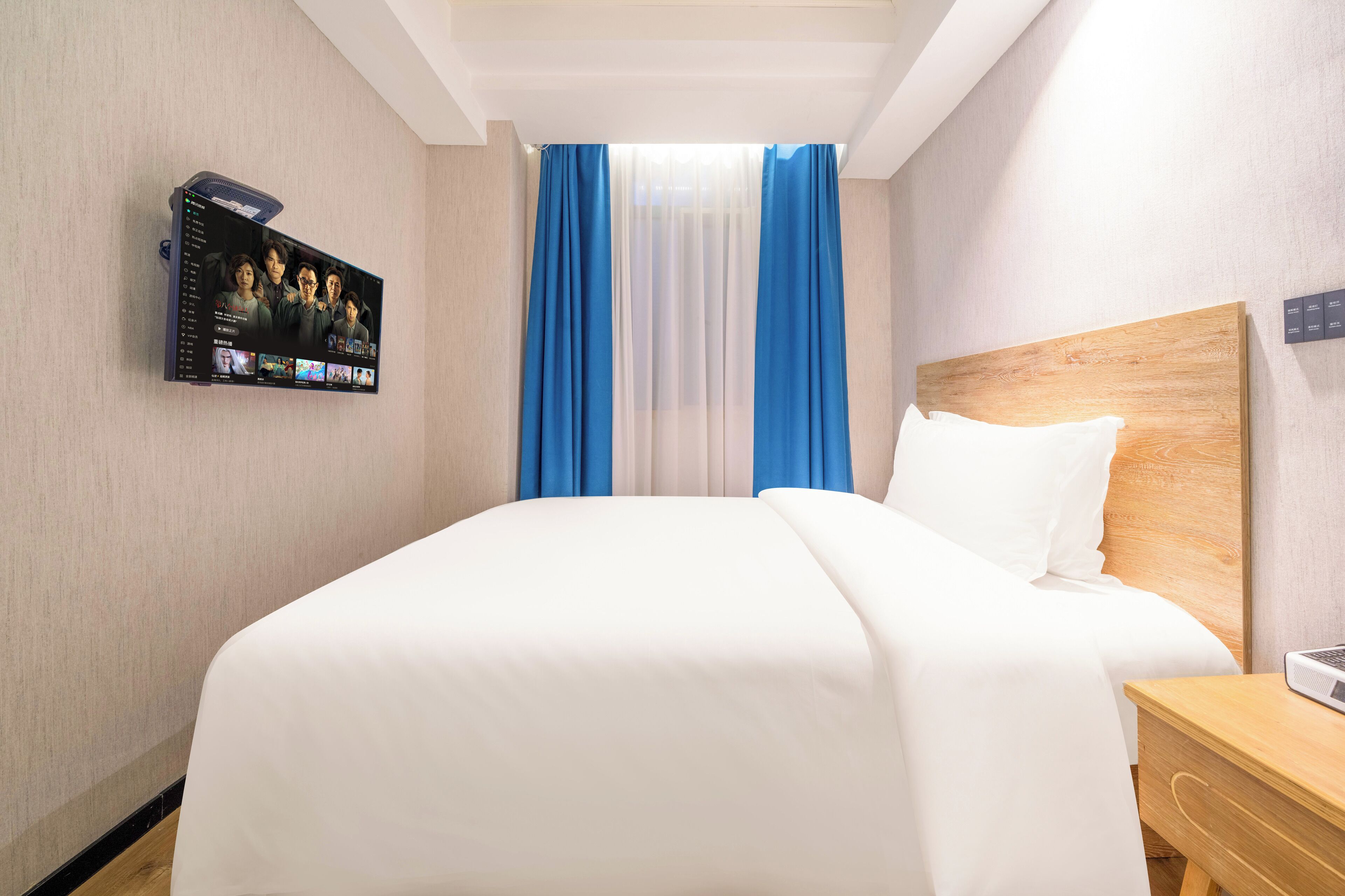 A hotel room with a large bed, a TV mounted on the wall, and a wooden headboard.